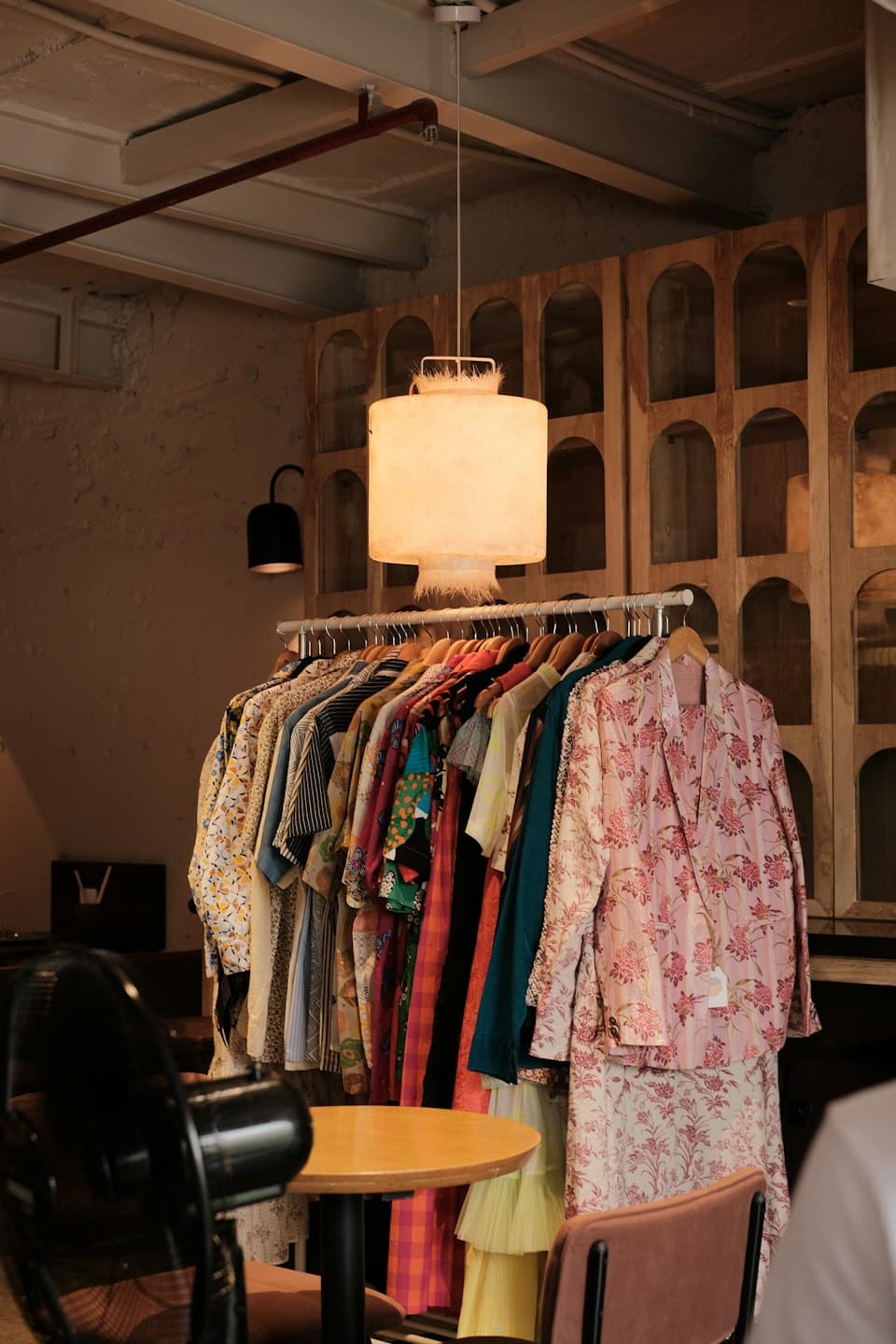 Colorful patterned garments hang on a rack inside a boutique.