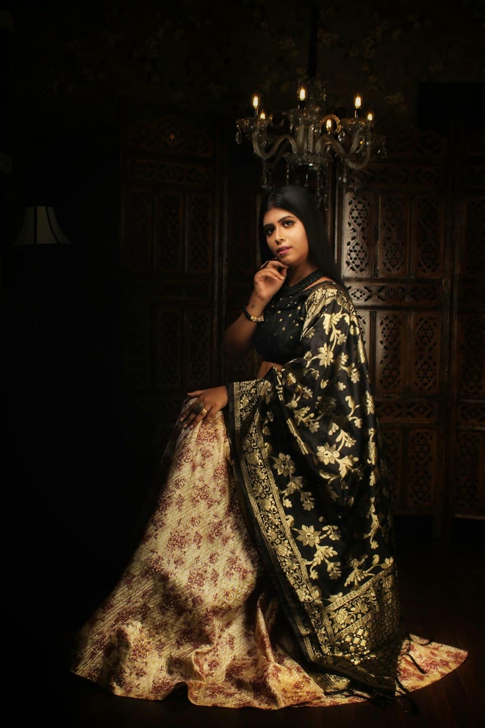 Woman in traditional attire rests her chin on her hand.