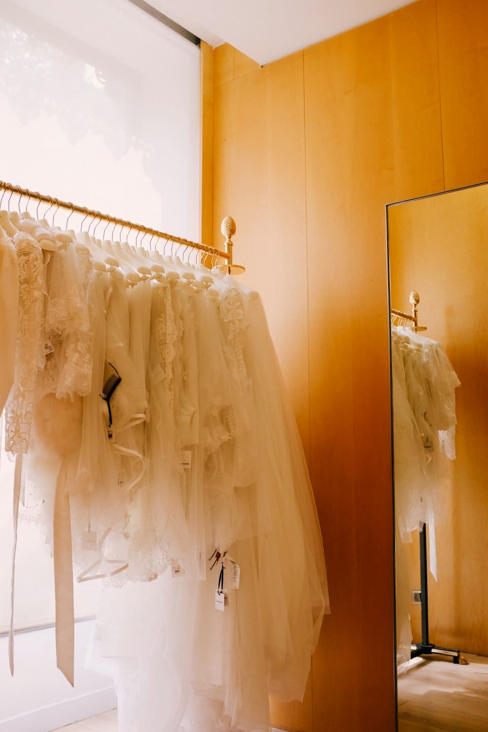 Elegant wedding dresses hang on a gold rail in a boutique.