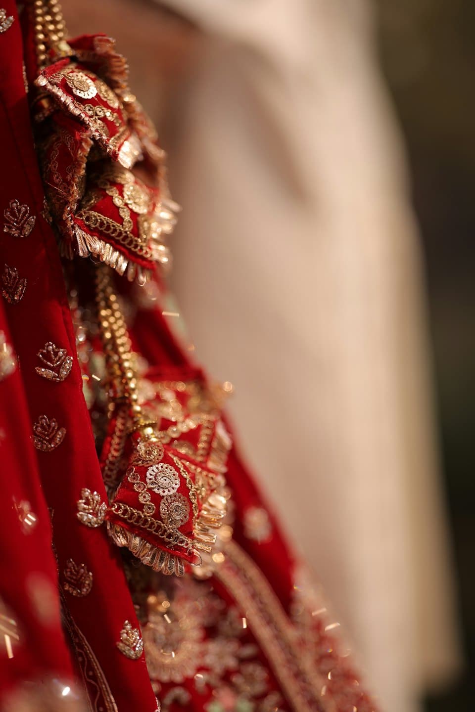 Intricate gold embroidery and sparkling sequins on red fabric.